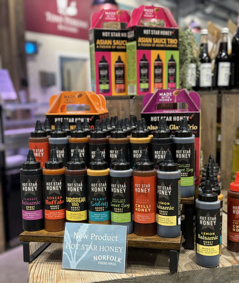 Display of various bottles of Hot Star Honey and Asian sauce trio packaging in a store setting.