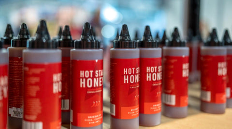 Multiple bottles of Hot Shot Honey on a table with a blurred background